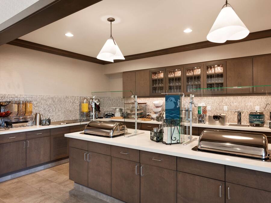 A modern kitchen with stainless steel appliances, a glass display case, and a breakfast bar.
