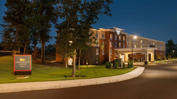 Hotel met een goed verlichte ingang, een bord en een aangelegde gazon.