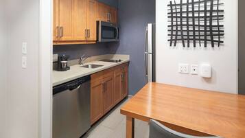 A compact kitchen with wooden cabinets, a microwave, a refrigerator, and a coffee maker.