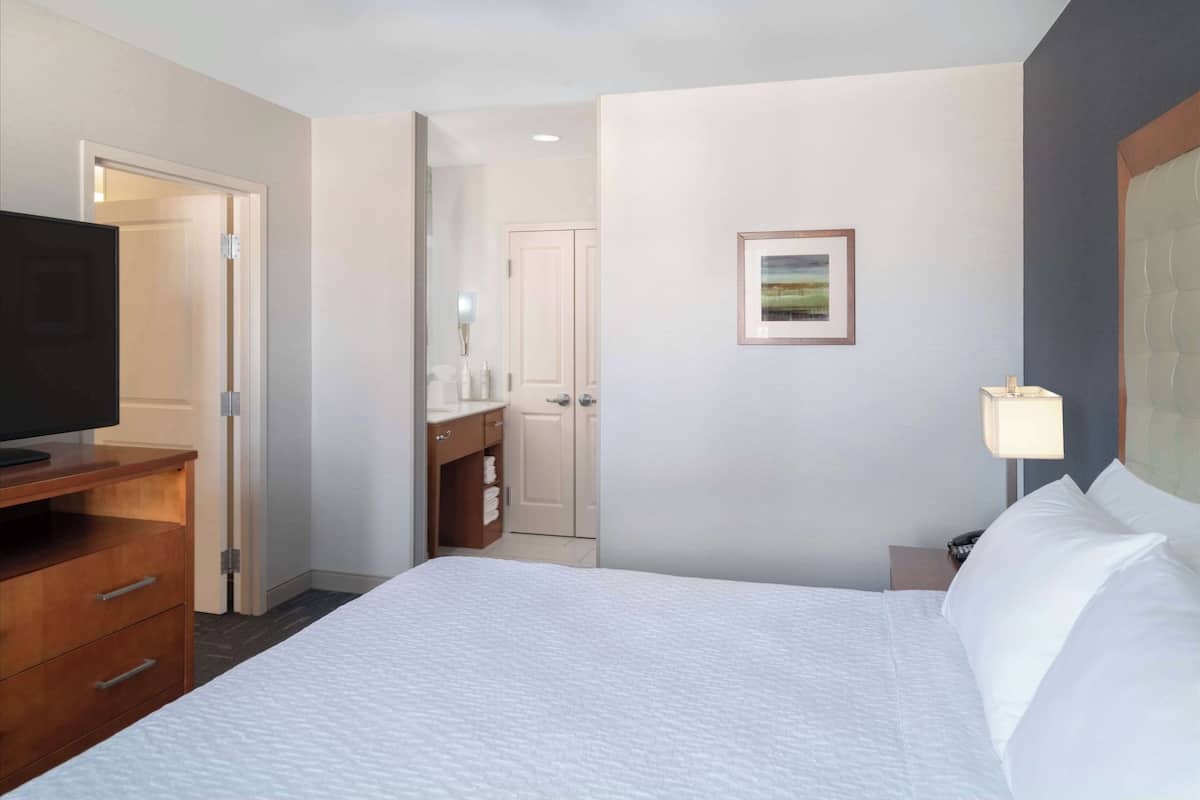 Een hotelkamer met een bed, een televisie, een bureau en een badkamer zichtbaar door een geopende deur.