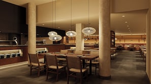 Un interno ristorante moderno con soffitti alti, illuminazione a sospensione e una zona pranzo centrale.