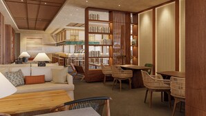 Una biblioteca moderna con estanterías, un sofá, sillas y una mesa de madera.