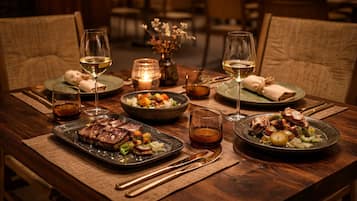 Una mesa de madera con platos de comida, copas de vino y velas.