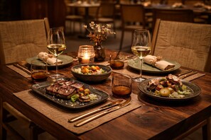 A wooden dining table with plates of food, glasses of wine, and candles. -  HD Sensarena - Adults Only (Teguise)