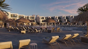 Un resort con piscina, lettini prendisole e ombrelloni di paglia.
