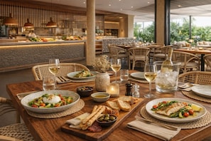 A restaurant setting with tables set for dining, featuring plates of food, glasses of wine, and a variety of condiments. -  HD Sensarena - Adults Only (Teguise)