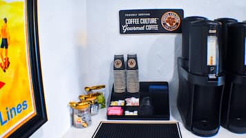 A coffee station with a sign reading "Coffee Culture Gourmet Coffee," stacks of cups, and a coffee machine.