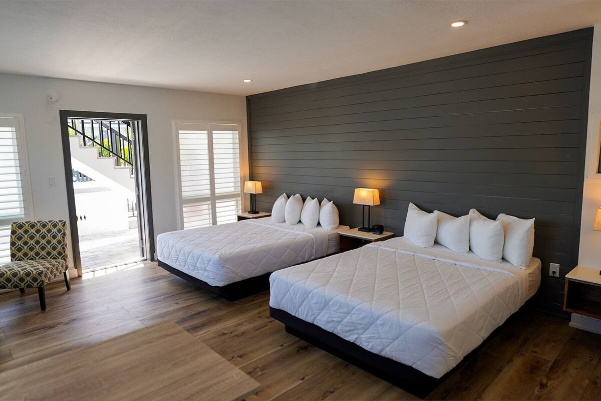 Habitación de hotel con dos camas, una silla y una escalera que conduce a un área exterior.