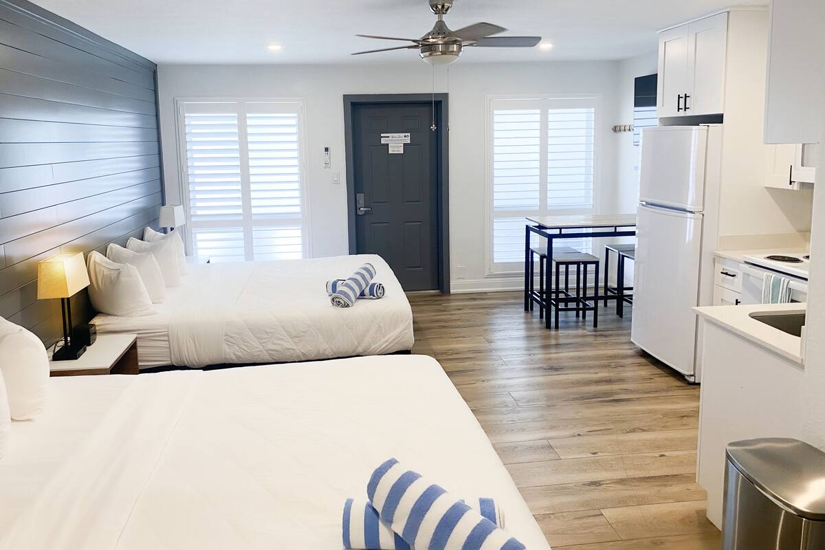 Habitación de hotel con dos camas, un kitchenette y una zona de comedor.