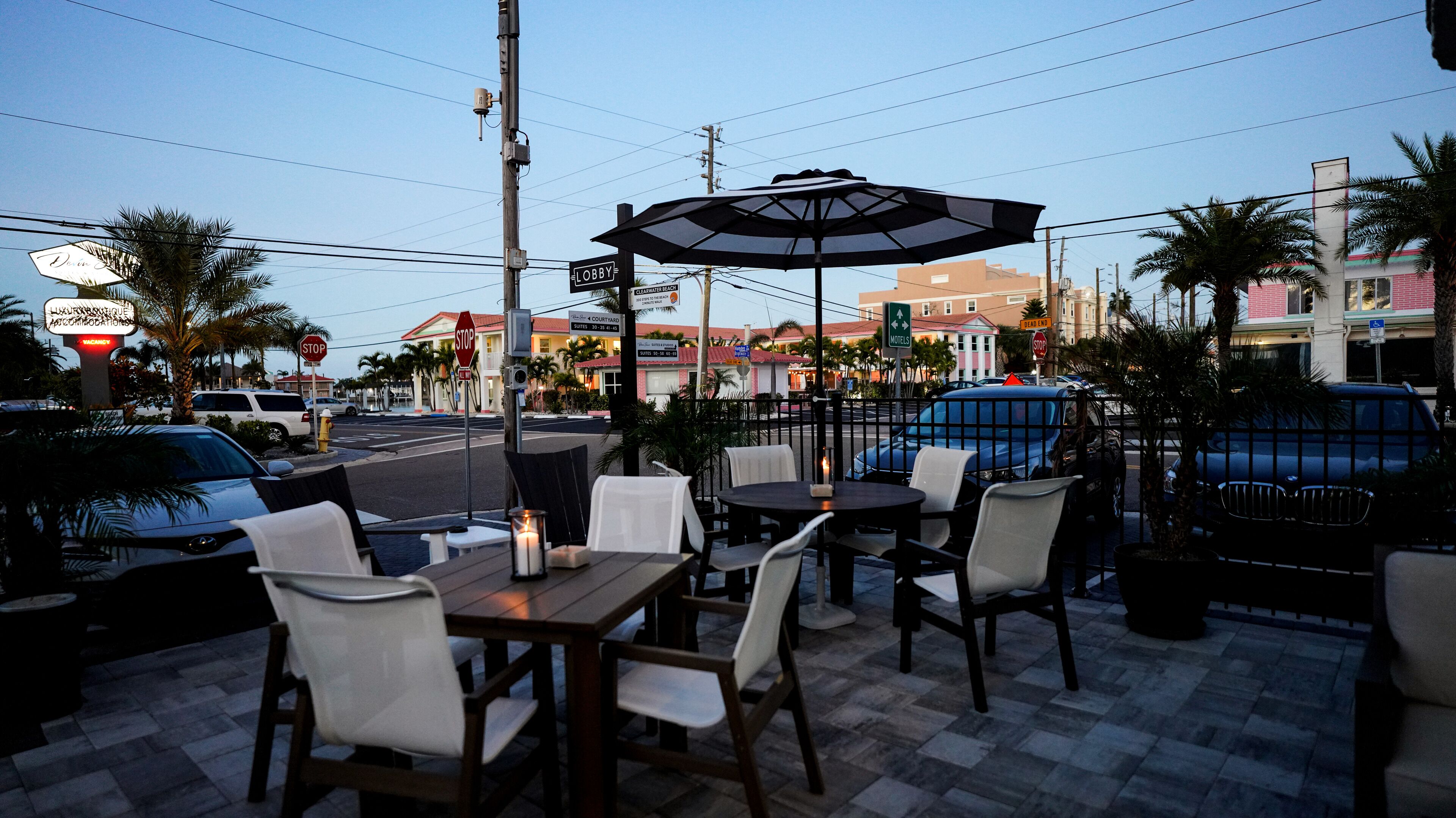 An outdoor seating area with tables and chairs, a stop sign, and a building in the background.
