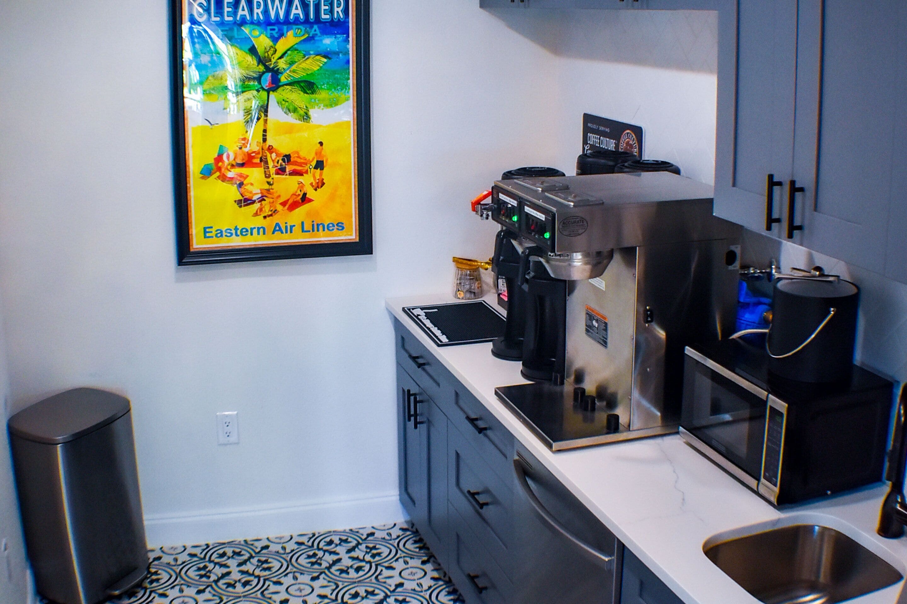 Una cocina moderna con cafetera, microondas y pileta de acero inoxidable.