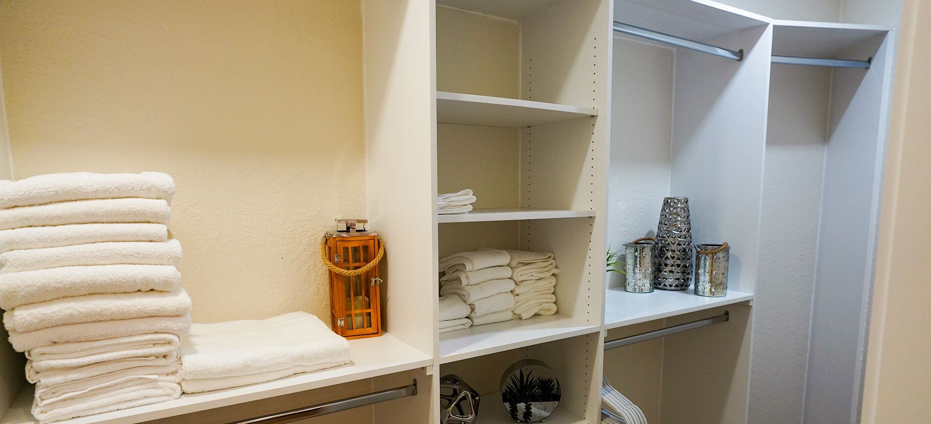 A neatly organized bathroom with shelves holding towels, a bottle, and decorative items.