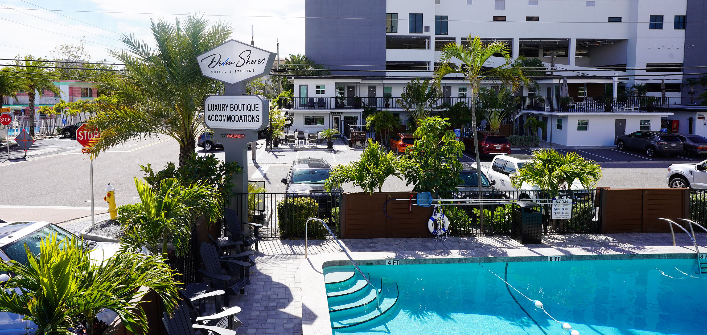 A luxury boutique hotel with a pool, outdoor seating, and a sign indicating available accommodations.