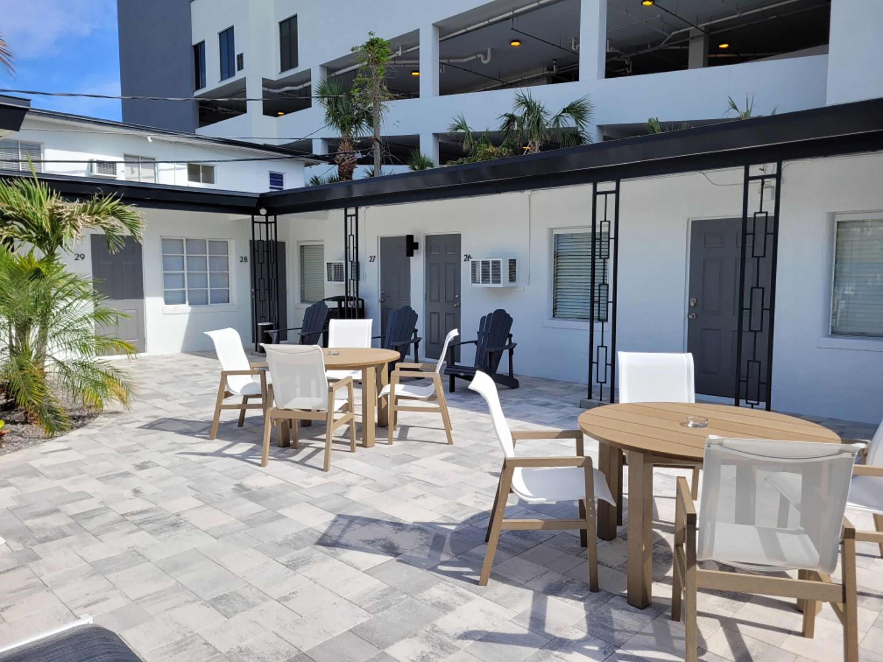 A courtyard with outdoor seating, a modern building with balconies, and a palm tree.