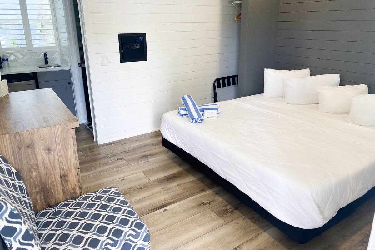 Una habitación de hotel moderna con una cama grande, un escritorio de madera y un sofá estampado.