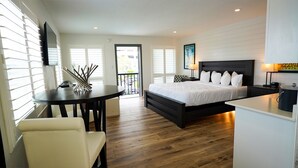 Un dormitorio moderno con una cama grande, un escritorio y una silla. Hay un balcón con vistas al exterior.