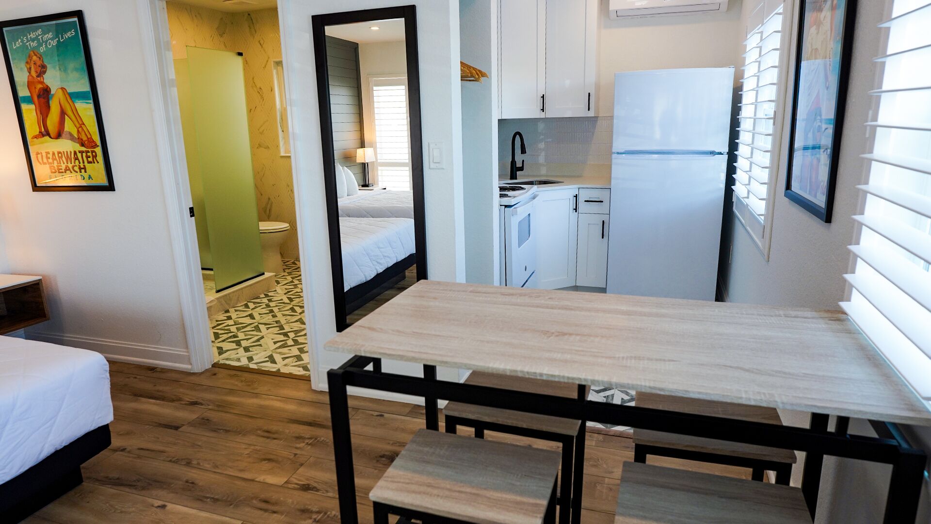 A compact hotel room with a bed, a small table, and a kitchenette.