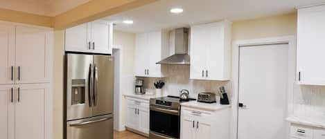 A modern kitchen with white cabinets, stainless steel appliances, and a built-in oven.