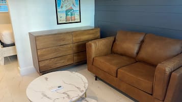 A brown leather sofa, a wooden cabinet, and a marble table with a remote control.