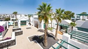 Um resort com edifícios brancos, palmeiras e céu claro.