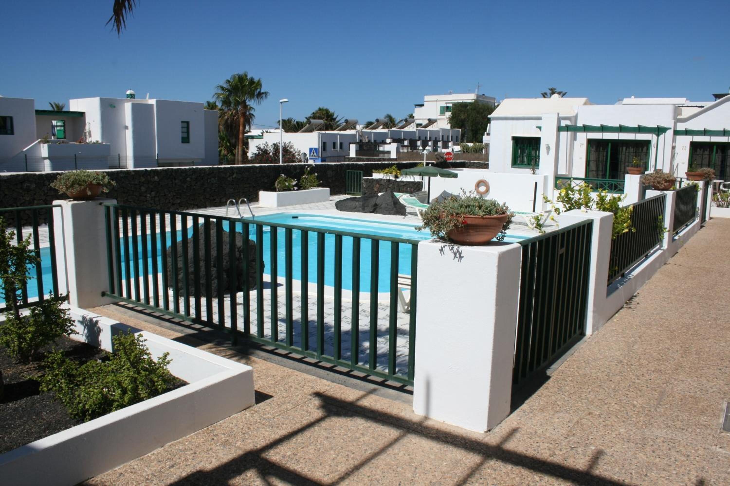 Zona de piscina al terrat amb vista clara als edificis circumdants i una paret de pedra.