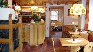 En restaurantindretning med en træbar, siddeområde og dekorativ belysning.