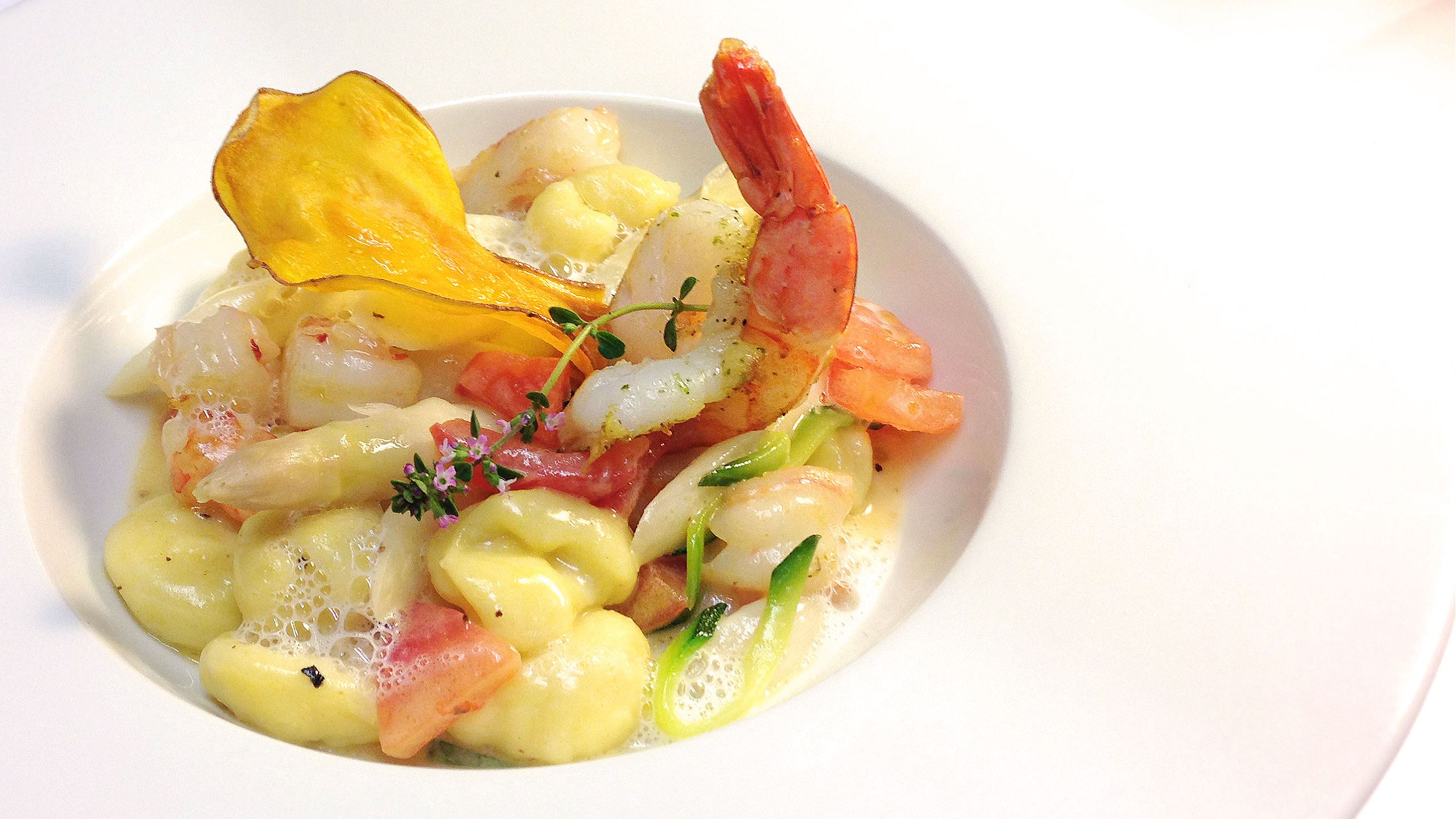 A plate of food with seafood, potatoes, and a garnish.