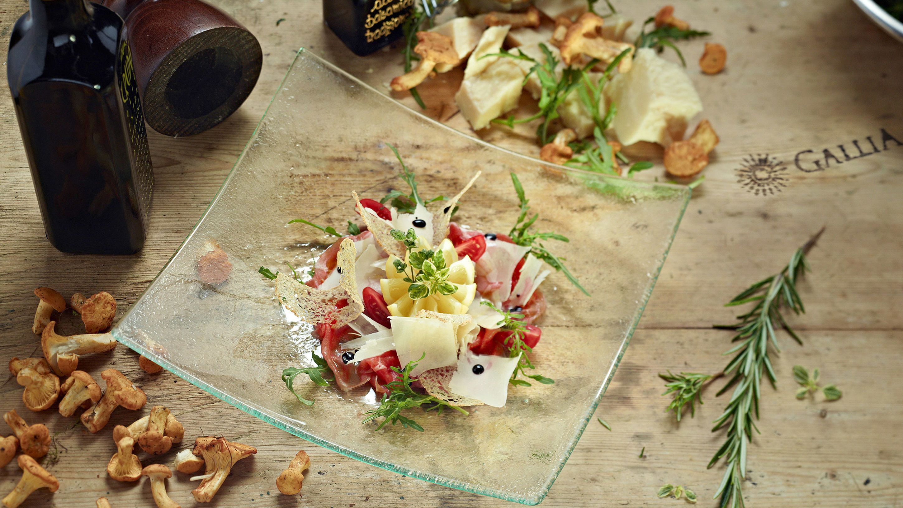 A glass plate with a food arrangement, surrounded by scattered mushrooms and a bottle.