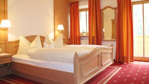 Una cama bien hecha con sábanas y almohadas blancas, un cabecero de madera y una mesita de noche con una lámpara.