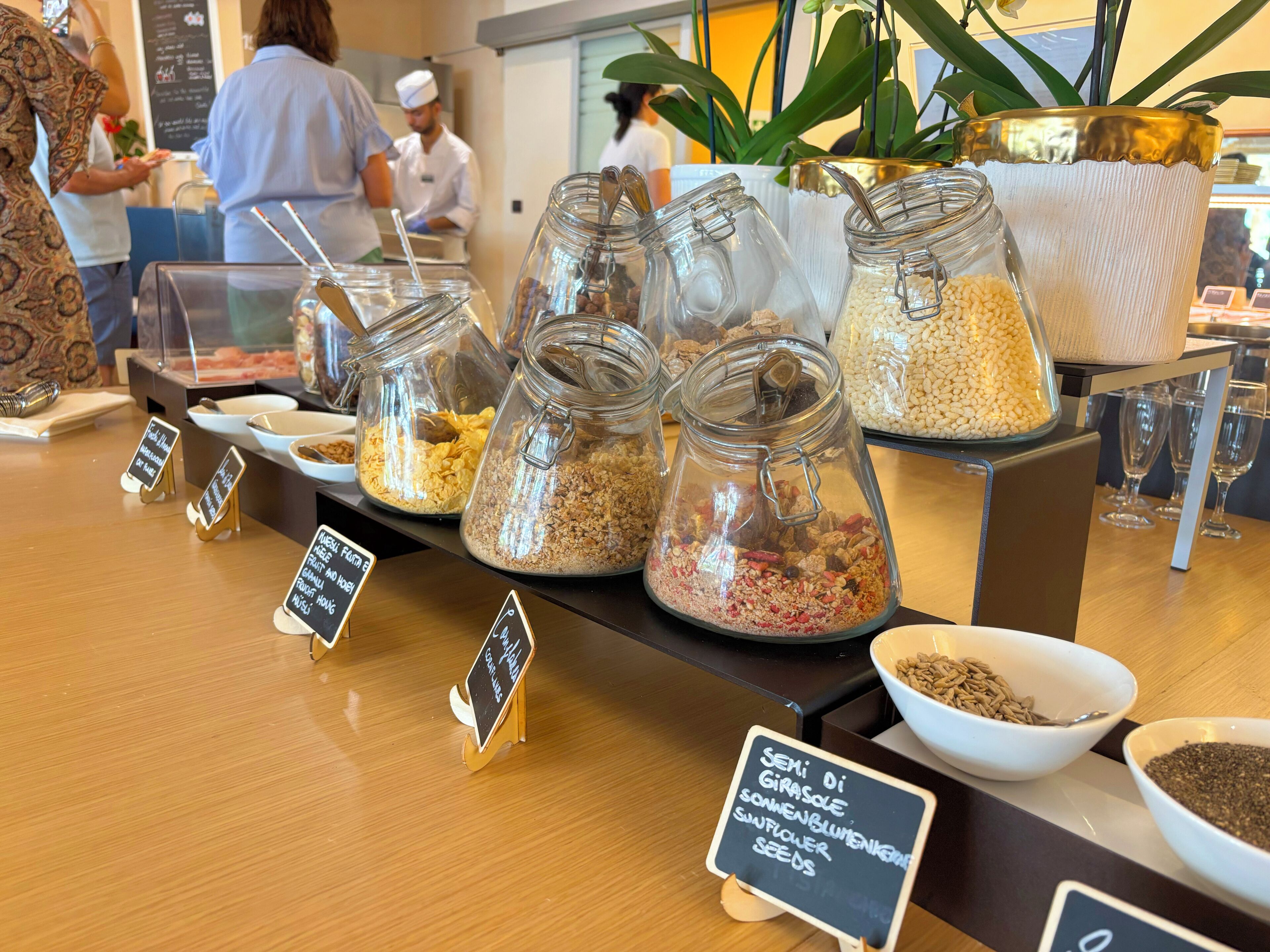 A food display with various jars of grains and seeds, a sign indicating the availability of fresh fruit and nuts, and a sign for sunflower seeds.