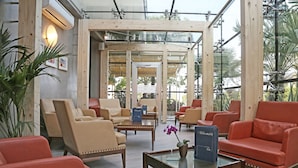 Un moderno vestíbulo de hotel con sofás de cuero, una mesa de centro de vidrio y vistas al exterior.