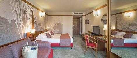 A hotel room with two beds, a desk, a chair, a sofa, a large mirror, and a wall with a unique textured design.