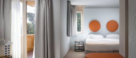 Habitación de hotel moderna con cama, una mesita, un banco y vistas a través de la puerta.