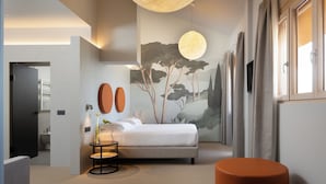 Un dormitorio moderno con una cama grande, una lámpara colgante redonda, un televisor montado en la pared y un cuadro de árboles.