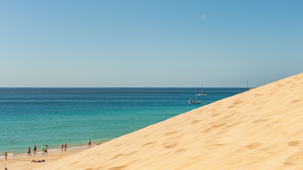 A beach with sand dunes and a clear blue sea. - NataLis Apartamentos (Pajara)