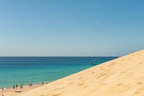 A beach with sand dunes and a clear blue sea. - NataLis Apartamentos (Pajara)
