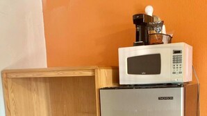 Une petite cuisine équipée d’un réfrigérateur en acier inoxydable, d’un four à micro-ondes et d’un meuble en bois avec des tiroirs.