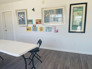 A room with a white table, black chairs, and a wall decorated with framed pictures and small posters.