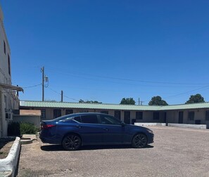 Un coche azul estacionado frente a un edificio con techo verde.
