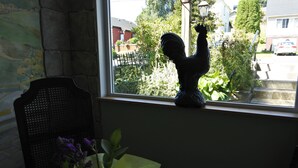 A window sill with a decorative statue, a chair, and a potted plant. - Black Rooster Guesthouse (Prince Rupert)