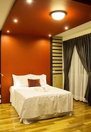 A hotel room with a large bed, a ceiling light, and a window with curtains.