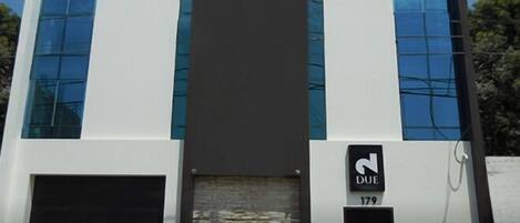 A modern building with a large entrance, two black doors, and a sign indicating 'DUE 179'.