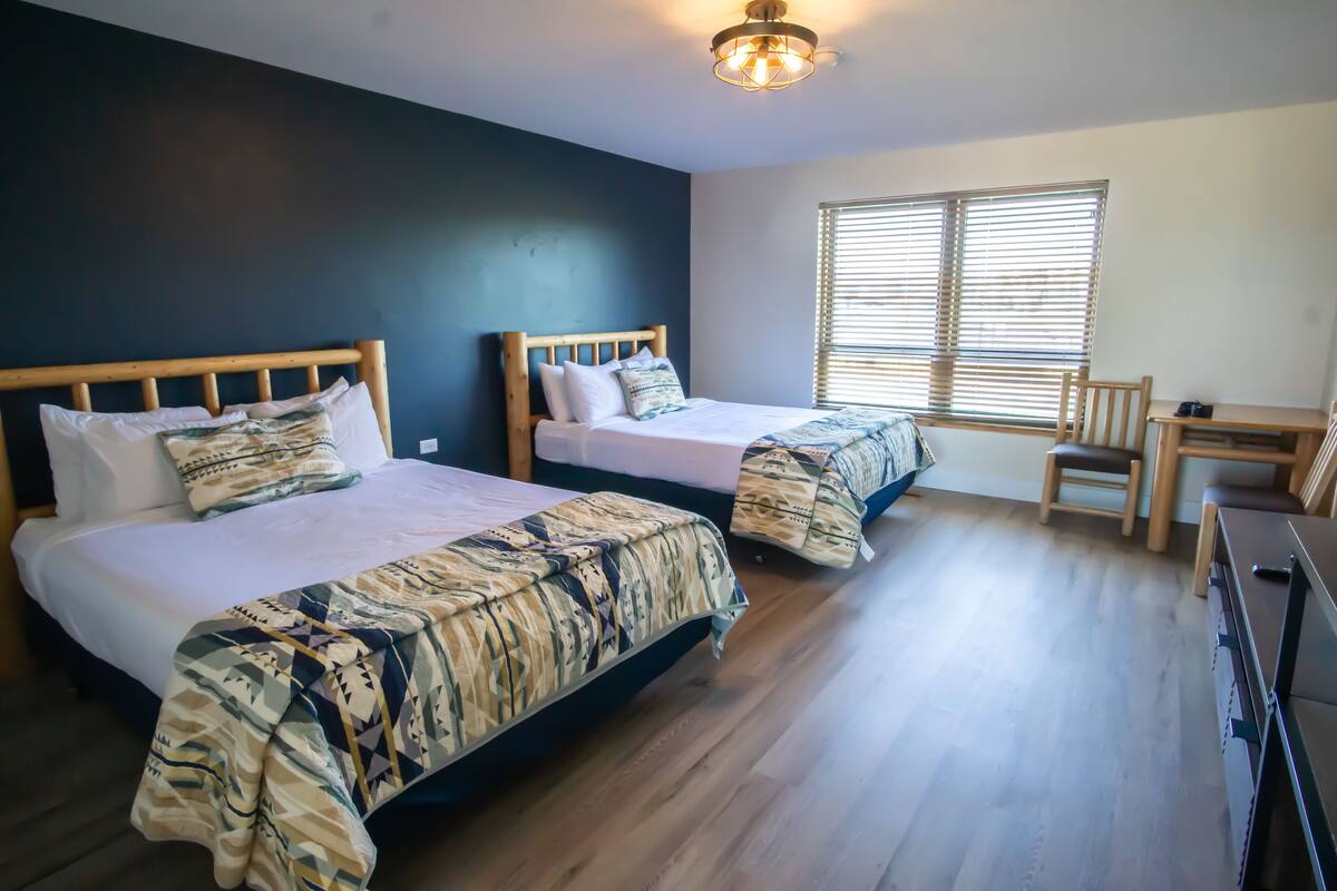 A room with two beds, a desk, and a chair.