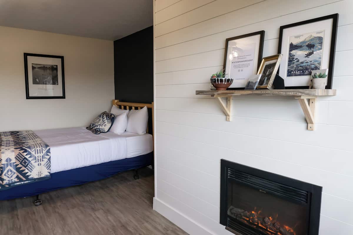 Un dormitorio con cama, chimenea y cuadros en la pared.