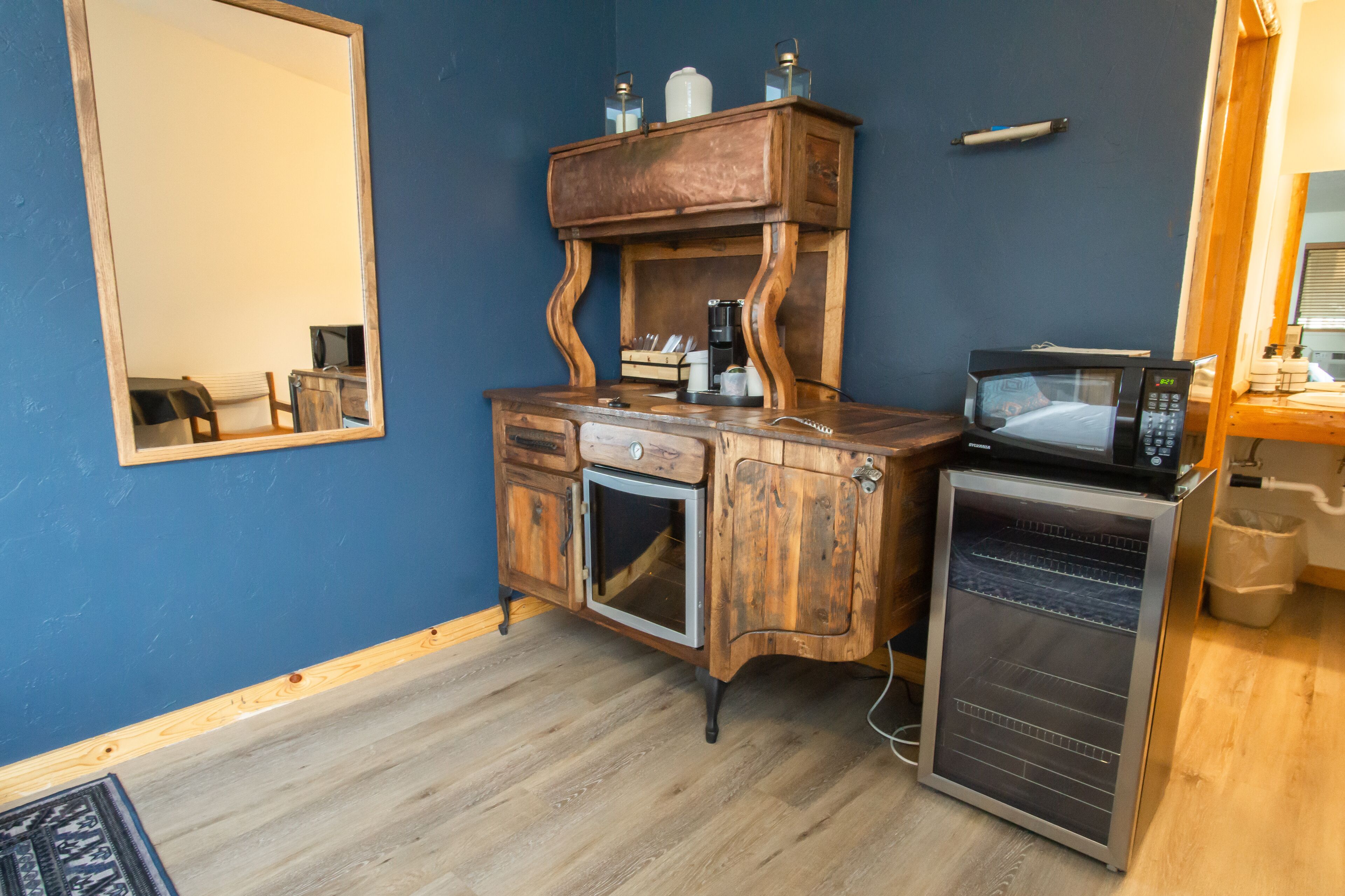 A compact kitchenette with a wooden cabinet, a microwave, and a small refrigerator.
