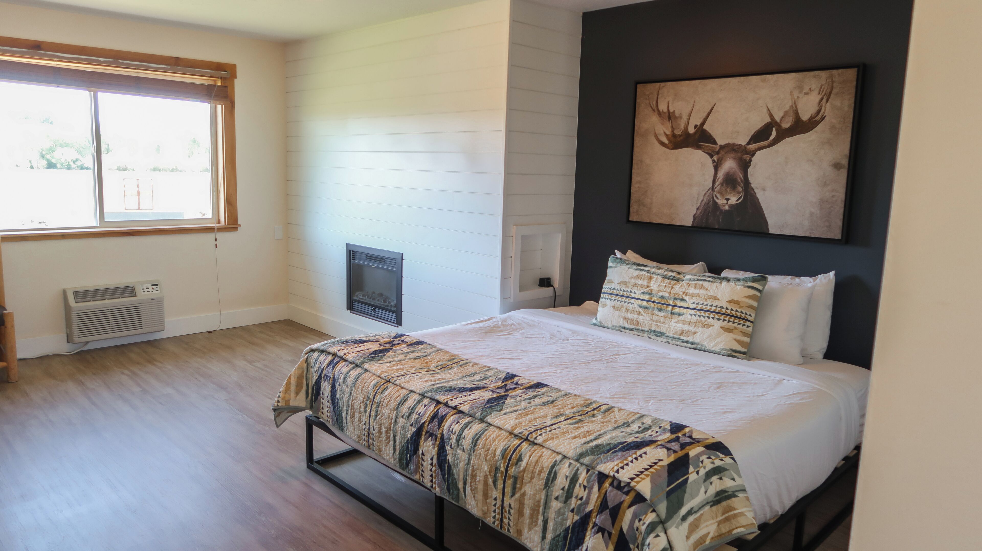 Une chambre à coucher comprenant un lit, une fenêtre, une cheminée et une œuvre d’art représentant un cerf, accrochée au mur.