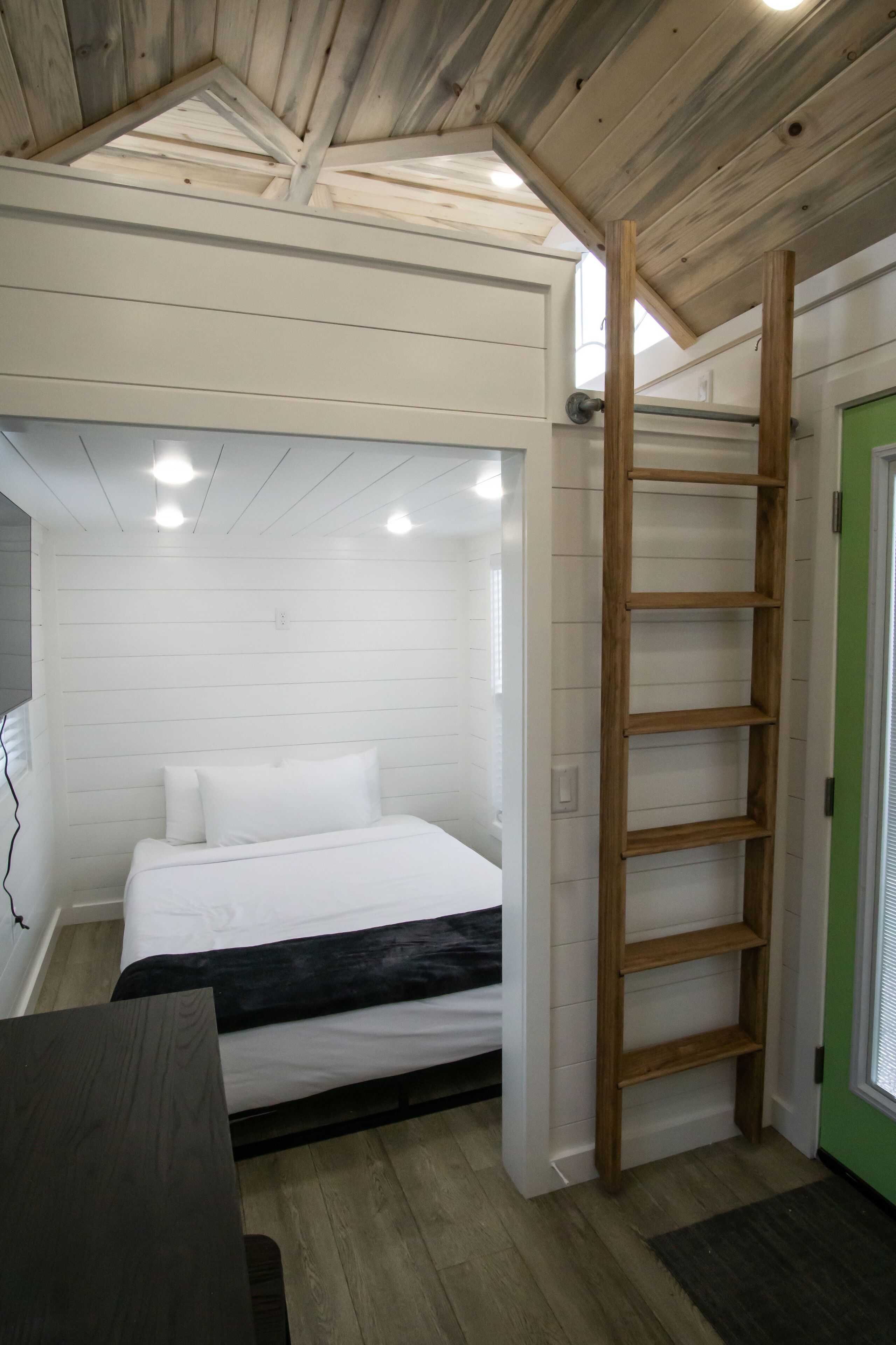 Ein Schlafzimmer mit einem Bett, einer Holzleiter und einer grünen Tür.