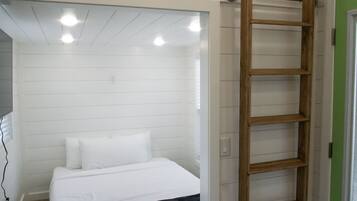 Ein Schlafzimmer mit einem Bett, einer Holzleiter und einer grünen Tür.