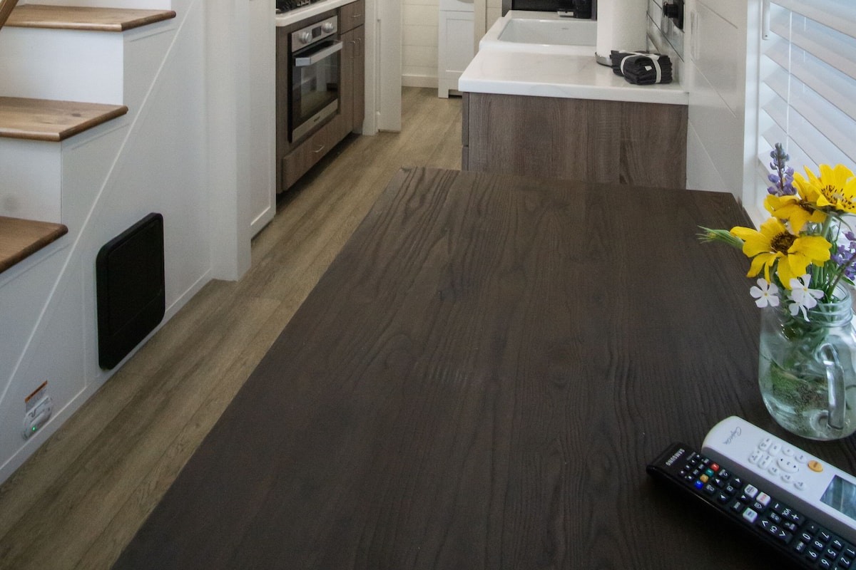 A modern kitchen with wooden flooring, a built-in oven, and a microwave.