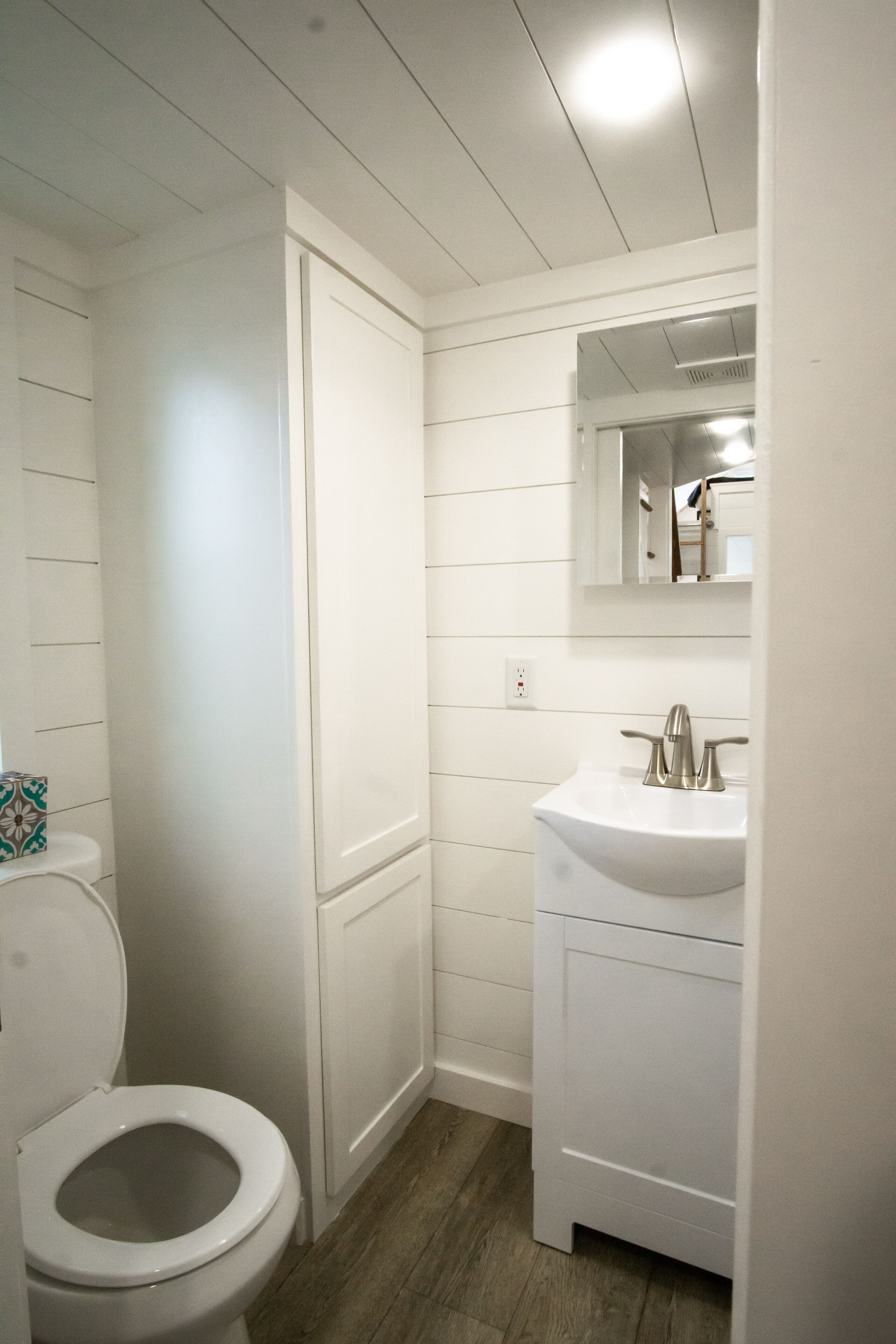 A bathroom with a white toilet, a sink, and a mirror above it.
